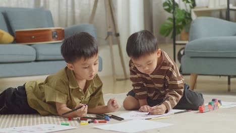 close up of asian kids sitting and lying on the floor in the room with plastic toy brick drawing together at home