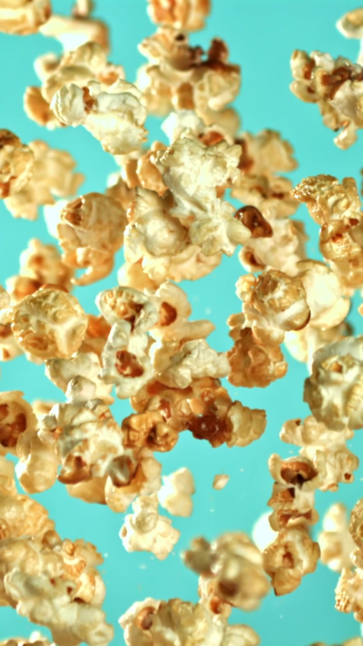 Popcorn al Caramello Che Cadono al Rallentatore su Sfondo Turchese