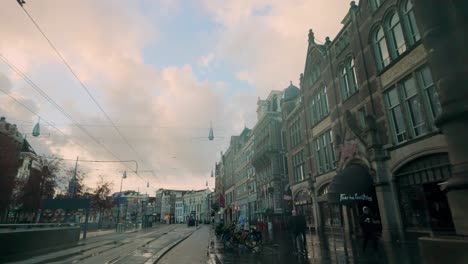rokin street in amsterdam during the morning with tram tracks, historic architecture, and a prominent stone column. the calm atmosphere is enhanced by soft lighting and pastel skies