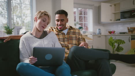 Pareja-Desempacando-Cajas-Después-De-Mudarse-A-Una-Nueva-Casa-Con-Una-Computadora-Portátil-Y-Bebidas-Calientes