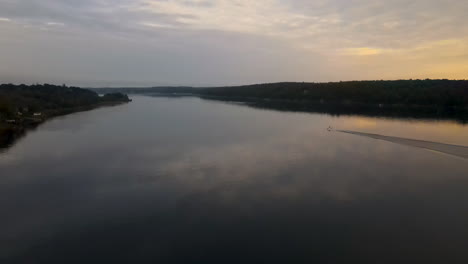 aerial footage of calm kennebec river, sunset, boat in distance moving on river