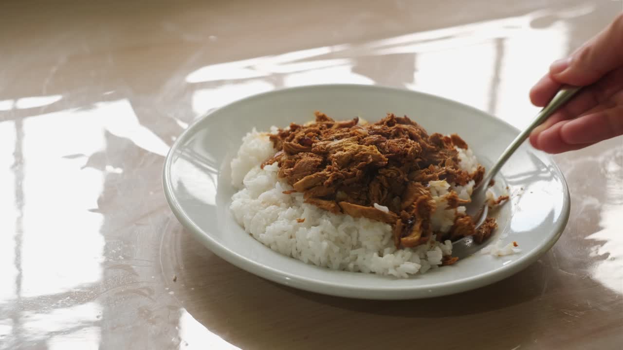Person Eating Steamed Rice Topped With Chicken Pastil. - closeup shot