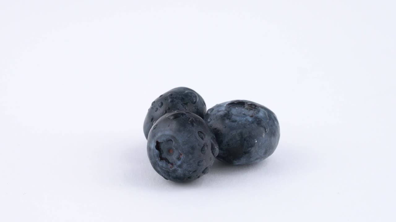 3개의 블루베리 베리는 색 바탕에 빠르게 회전합니다. 고립되어 있습니다. 루프가 가능합니다. 클로즈업.