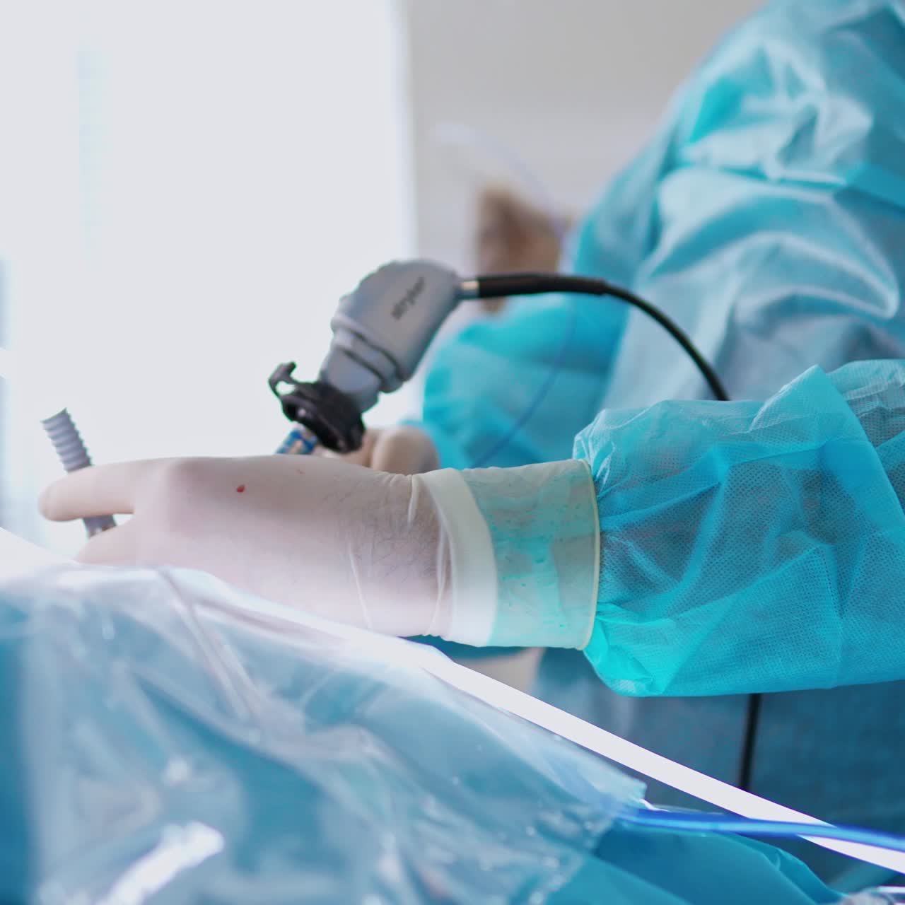 Surgical instrument in doctor's hands. Medical specialist in sterile gloves performing a surgery with a modern equipment on monitor background. Close-up.