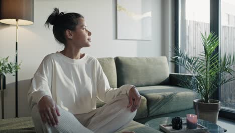 mujer natural meditando en casa y mirando en el lado del sol.