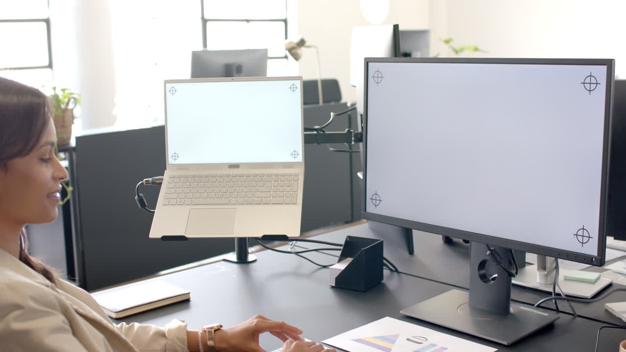 Working in office, woman using laptop and desktop monitor for business tasks, copy space