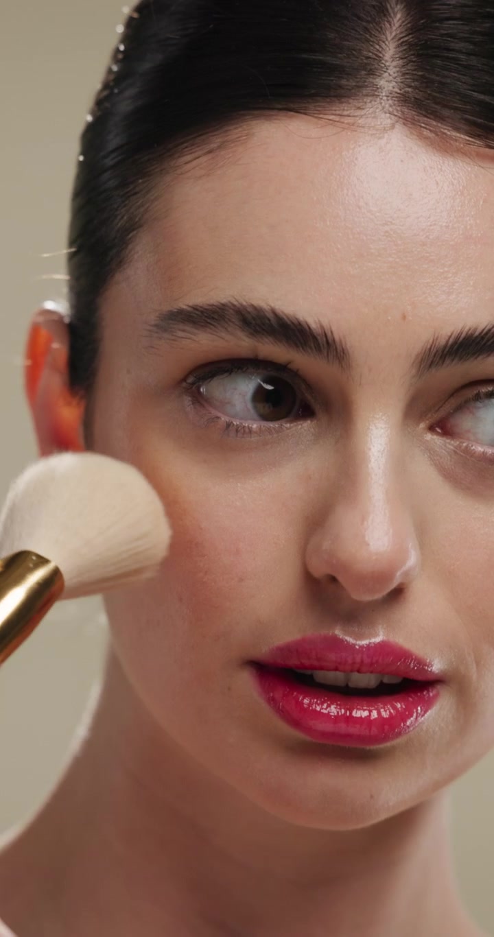 Young Woman Applying Blush with Makeup Brush