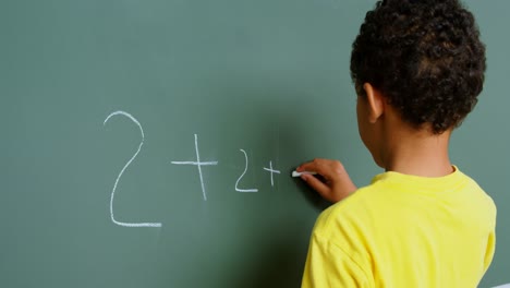 Vista-Trasera-De-Un-Colegial-Afroamericano-Resolviendo-Problemas-Matemáticos-En-Una-Pizarra-En-El-Aula-De-La-Escuela-4k