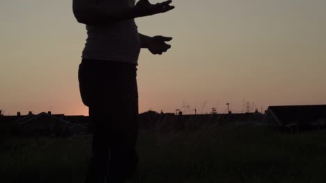 woman in solitude silhouette throwing a ball into air at sunset