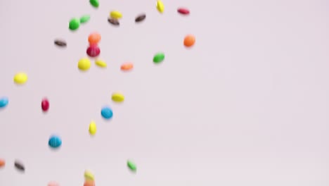 colorful chocolate candies fall through the air on white back drop