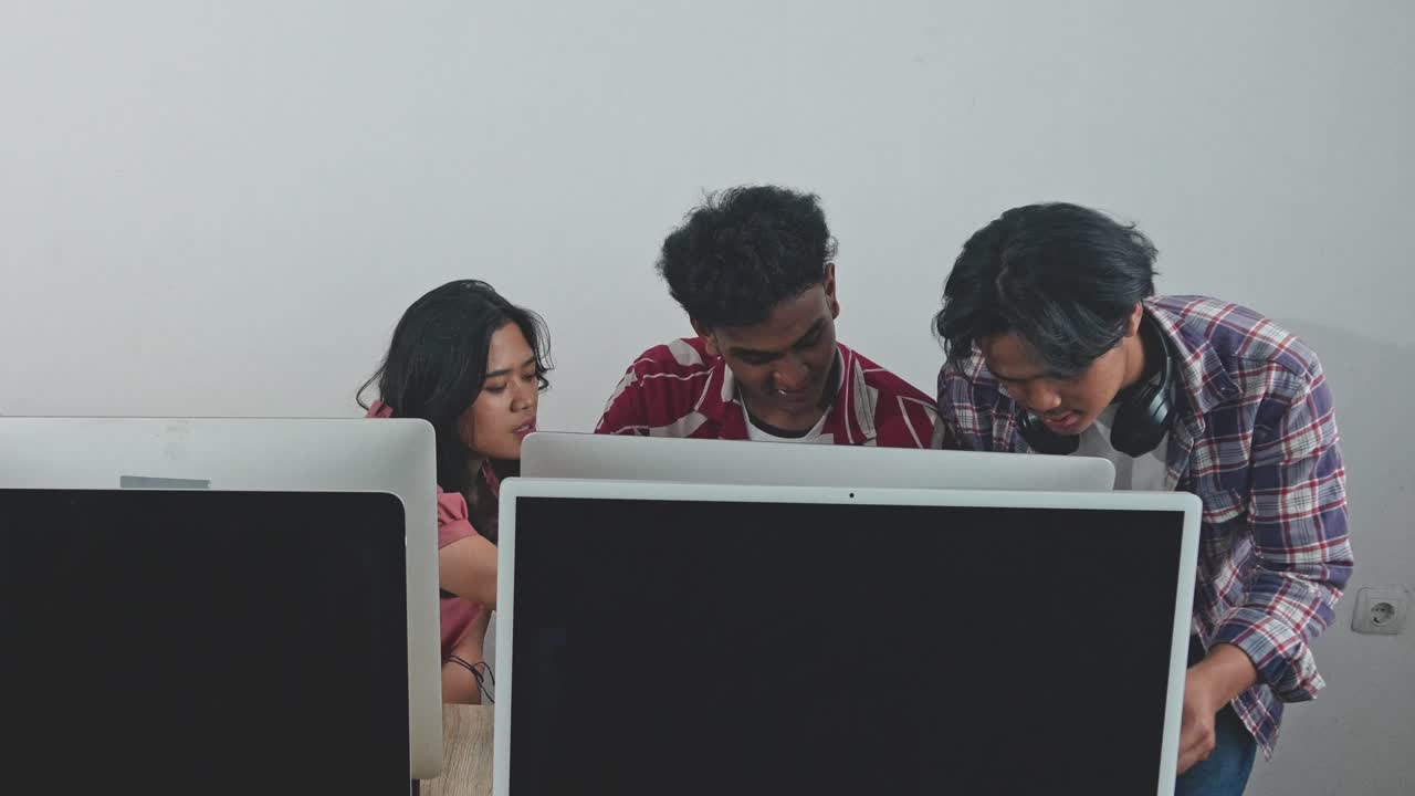 Group Of Young Asian Graphic Designers Looking At Computer Screen And Working Together