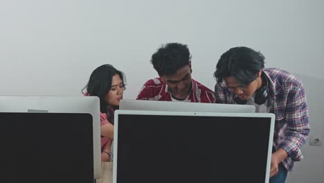 group of young asian graphic designers looking at computer screen and working together