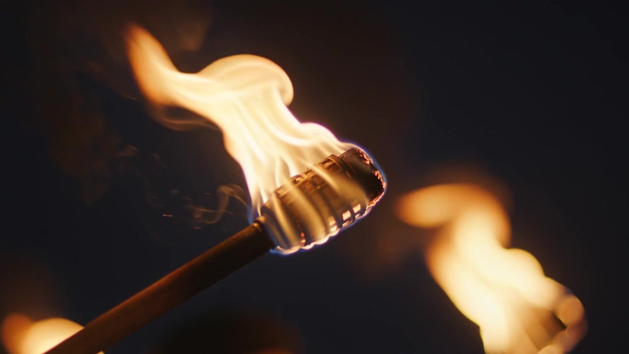 Emerging flame causing handheld torch curling and flickering at night from breeze, metal-caged head