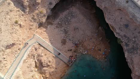 Drehende-Drohnenaufnahme-Von-Bimmah-Sinkhole-Mit-Türkisfarbenem-Wasser-In-Der-Nähe-Von-Muscat-Im-Sultanat-Oman
