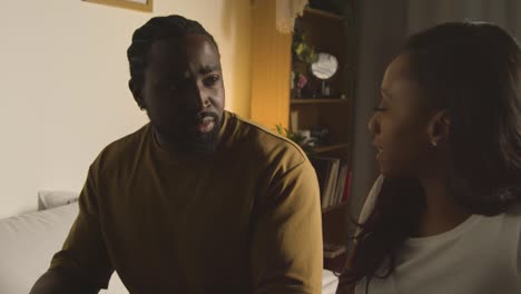 couple at home sitting on bed at night having argument 2