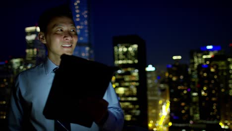 consultor masculino asiático chino usando pantalla táctil por la noche