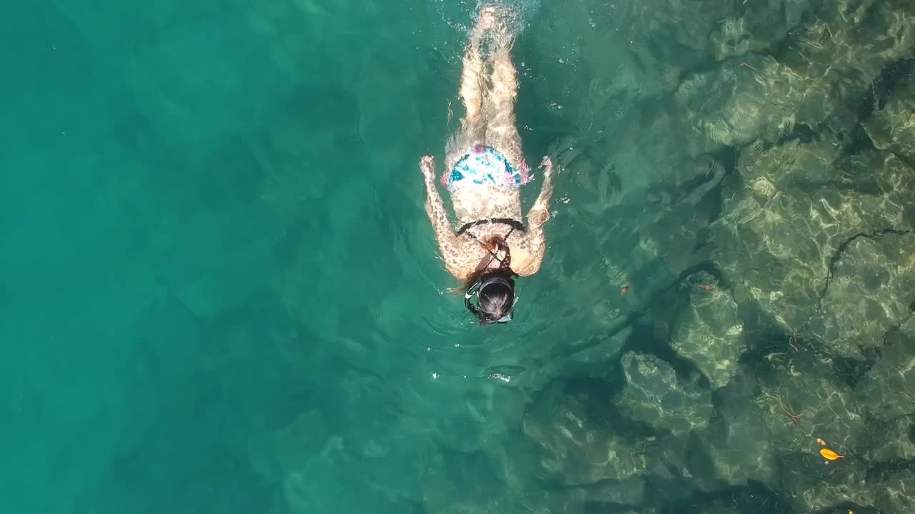 A female snorkeler in a bikini swimming along in the ocean