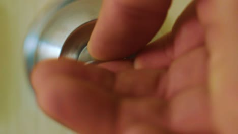 un hombre bloqueando un pomo de acero inoxidable girándolo en el sentido de las agujas del reloj - un primerísimo plano