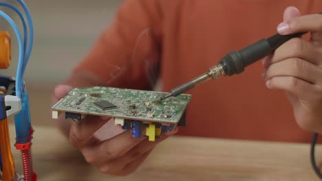 close up of asian boy's hand holding and fixing the circuit board while repairing a cyborg hand at home