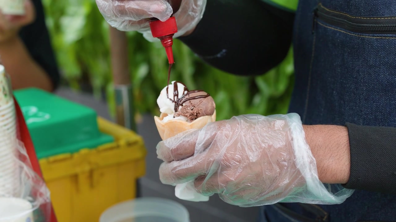 A vendor adds chocolate sauce to ice cream in a waffle bowl in Bangkok.