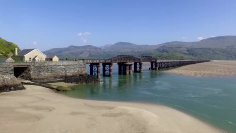 drone flying across the barmouth beach and over the railway bridge in wales in the uk