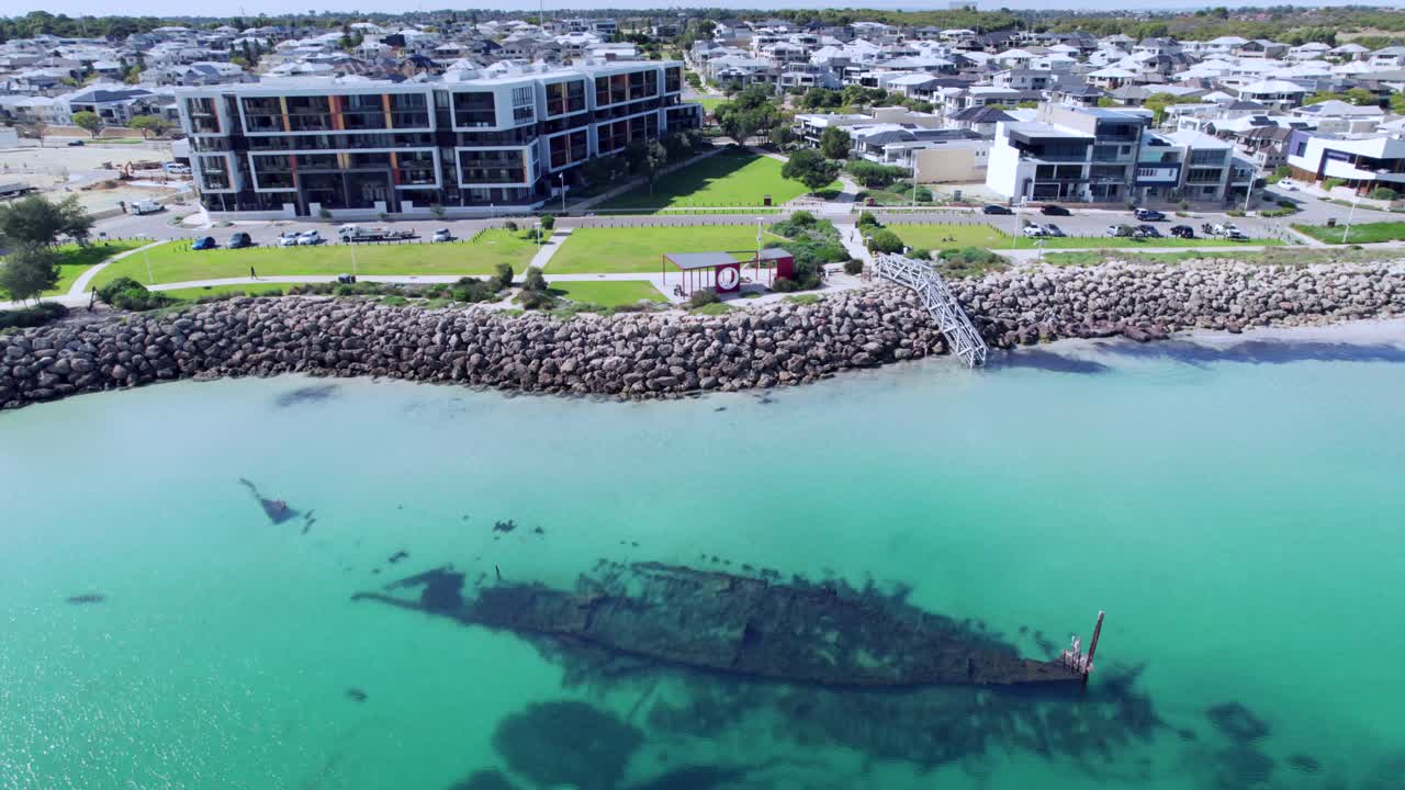 The Omeo wreck, a historic shipwreck located in Coogee, Western Australia. The wreck is surrounded by clear blue water and white sand, and the surrounding  modern apartment buildings