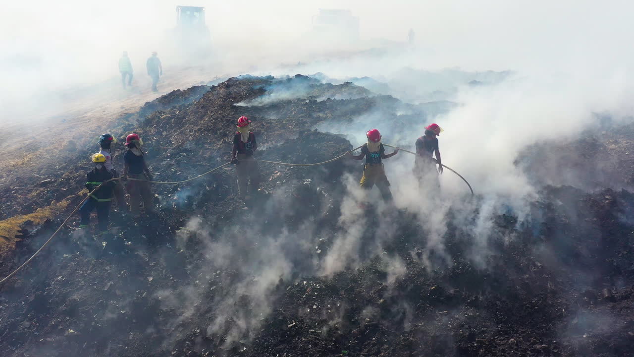 Aerial view around a group of Firefighters quelling a wildfire, smoke rising, sunny day, in Los Angeles, California, USA - Orbit, drone shot