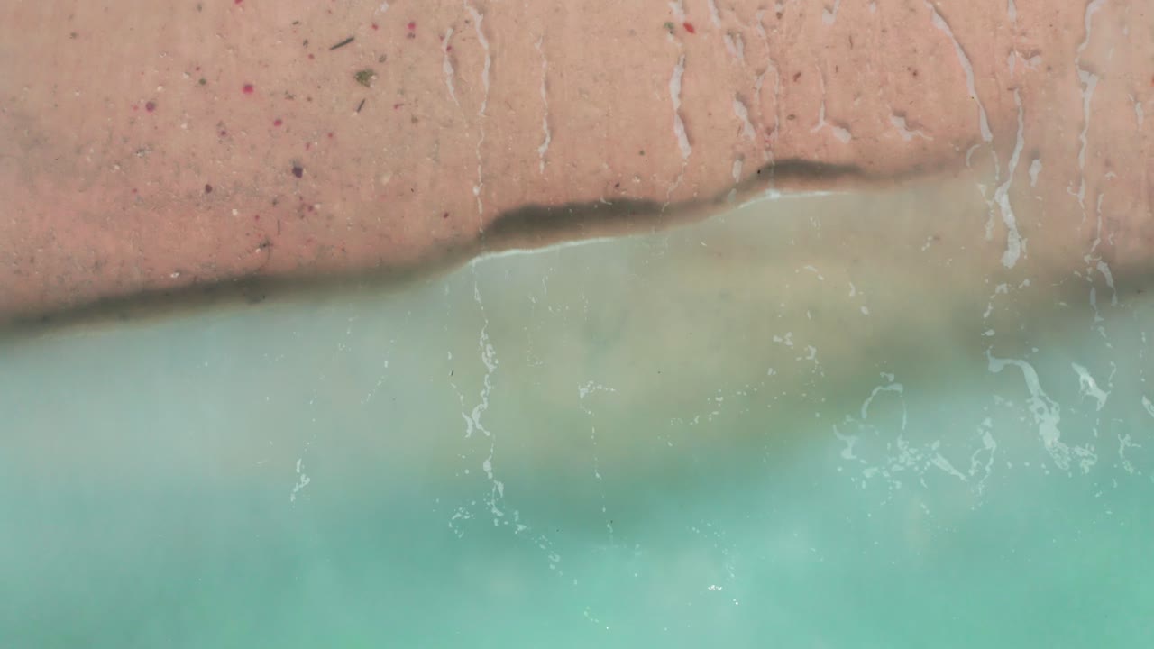 Aerial top view waves break on beach in a blue ocean