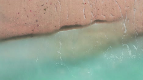 Aerial-top-view-waves-break-on-beach-in-a-blue-ocean