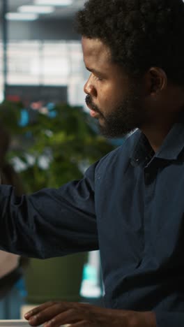 vertical video employee in office leaving desk to present revenue figures on tablet