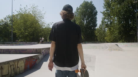 un chico caucásico caminando en el parque de skate.
