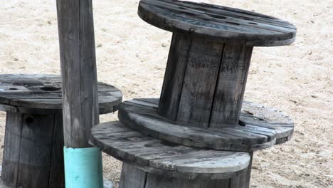 Wooden-beach-stools-stacked-on-the-sand