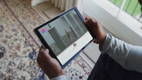 Composite-of-man-sitting-at-home-watching-athletics-running-event-on-tablet