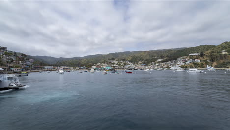 lapso de tiempo de la llegada del ferry y los barcos flotando en el puerto con nubes pasando por encima de la isla catalina en el océano pacífico del sur de california