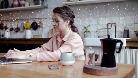 woman working on laptop in a cozy kitchen