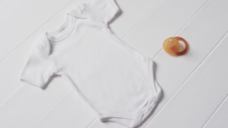 Video-of-white-baby-grow-and-dummy-with-copy-space-on-white-background