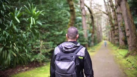 Sportsman-rearview-trekking-a-track-trail-through-mountains-walking-by-muddy-paths-after-rain-amidst-nature-in-the-middle-of-the-forest-and-jungle