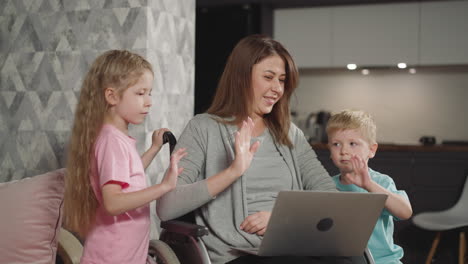 Happy-woman-and-kids-wave-hello-looking-at-screen-of-laptop