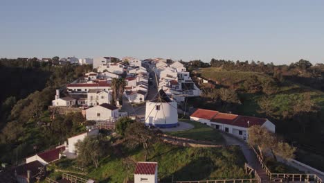 Side-panning-shot-of-old-white-windmill-at-Odeceixe-Portugal,-aerial