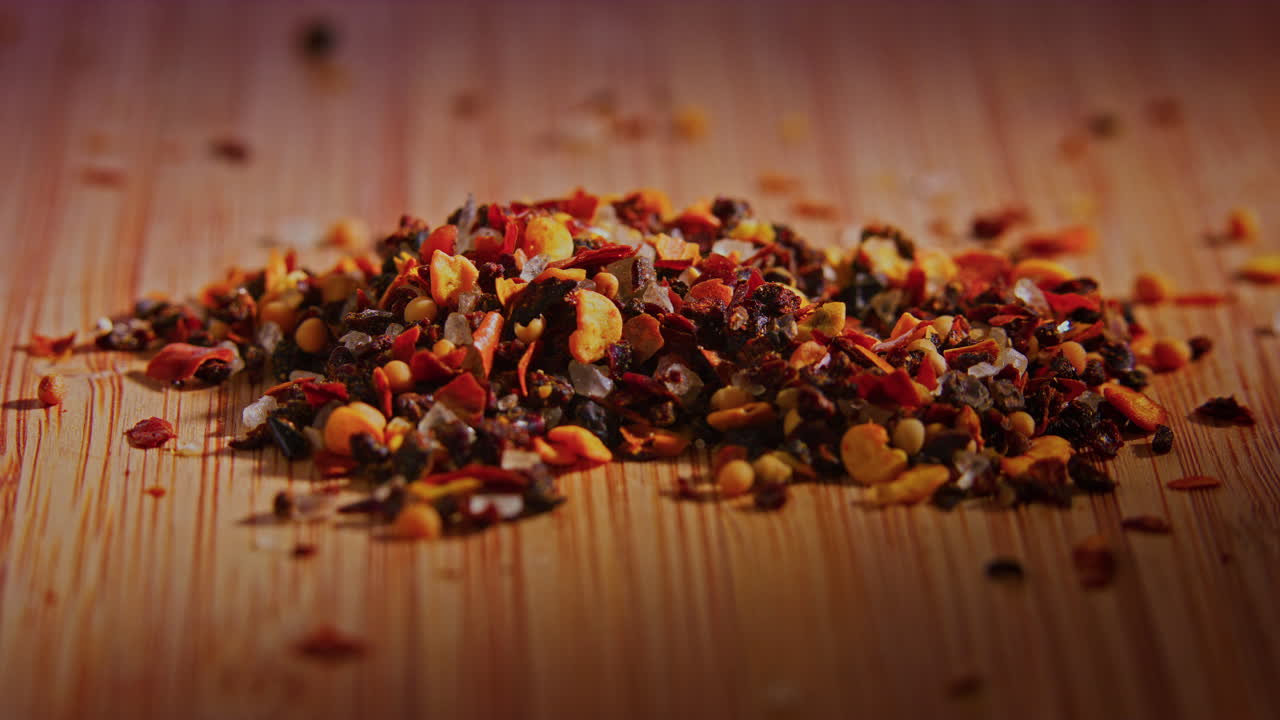 una pila de mezcla de especias de chile en una superficie de madera con iluminación dramática, cámara en órbita