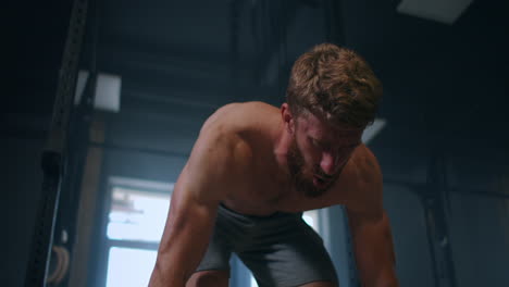 Wide-shot-of-young-Caucasian-extreme-weightlifting-athlete-man-working-out-with-heavy-barbell-in-large-hardcore-gym-hall.