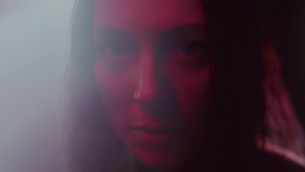 Retrato de mujer mirando fijamente a la cámara bajo una luz roja dramática.
