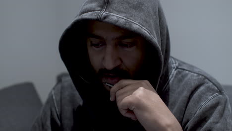 un hombre serio con una capucha gris oscuro y una barba y un bigote cuidadosamente hechos hablando por un micrófono de auricular