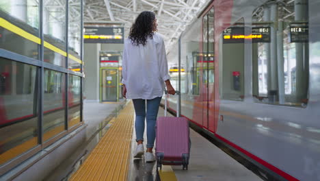 woman walking through train station with suitcase