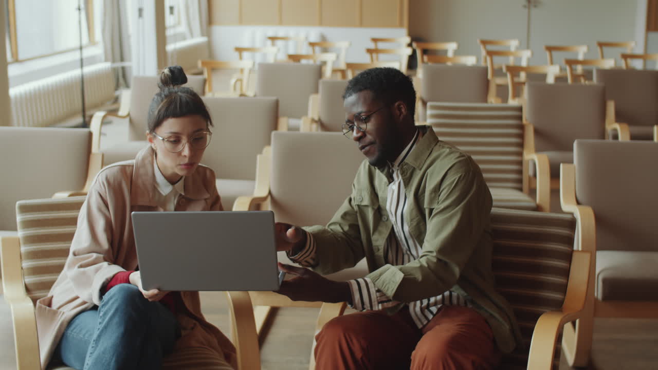 hombre y mujer discutiendo un proyecto en una computadora portátil en el auditorio de la biblioteca