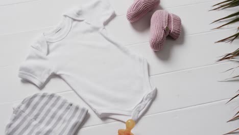 Video-of-white-baby-grow,-hat,-dummy-and-pink-booties-with-copy-space-on-white-background