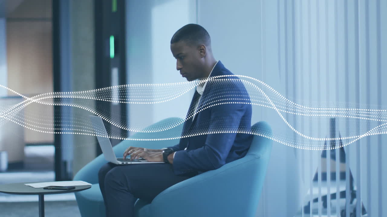 Animation of spots moving over african american businessman using laptop in office