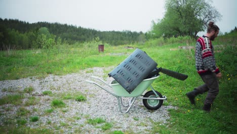 man loading wheelbarrow with plastic waste. - static