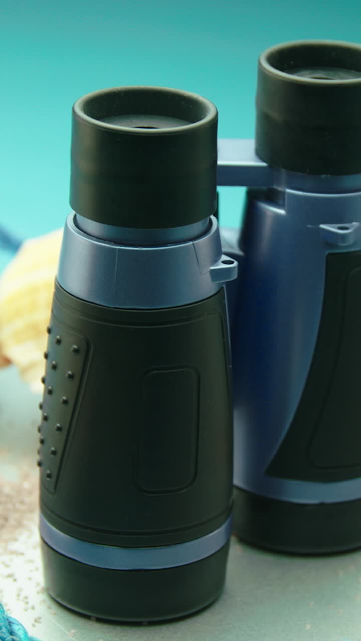 Rotating binoculars with beach elements, representing summer adventure, travel and exploration
