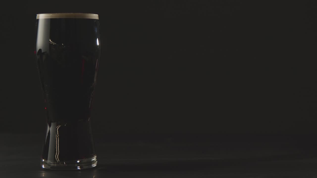 성 패트릭의 날 1을 축하하기 위해 검은색 스튜디오 배경에 유리에 아일랜드 스타우트 파인트